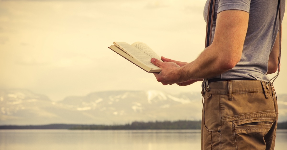 Seorang pria sedang membaca buku saat traveling